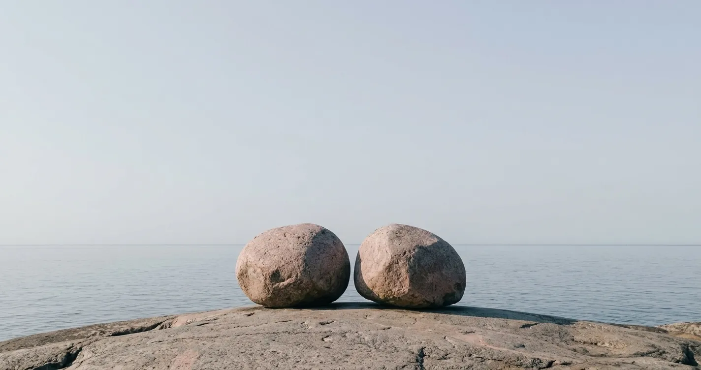 Kaksi kiveä vierekkäin rantakalliolla tyynen meren edessä